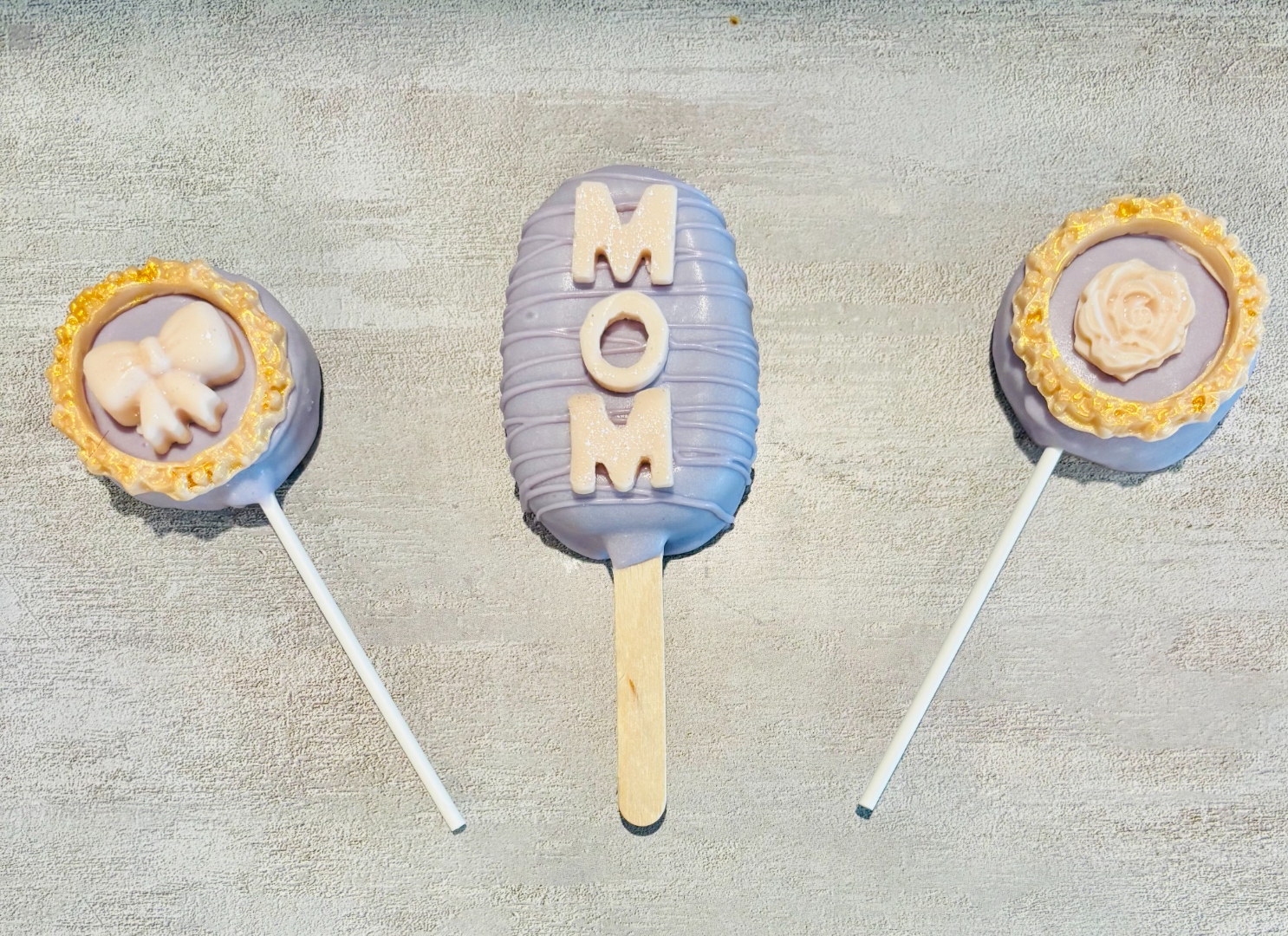 Lavender cakecicle and cake pucks decorated for Mother's Day with gold-trim accents